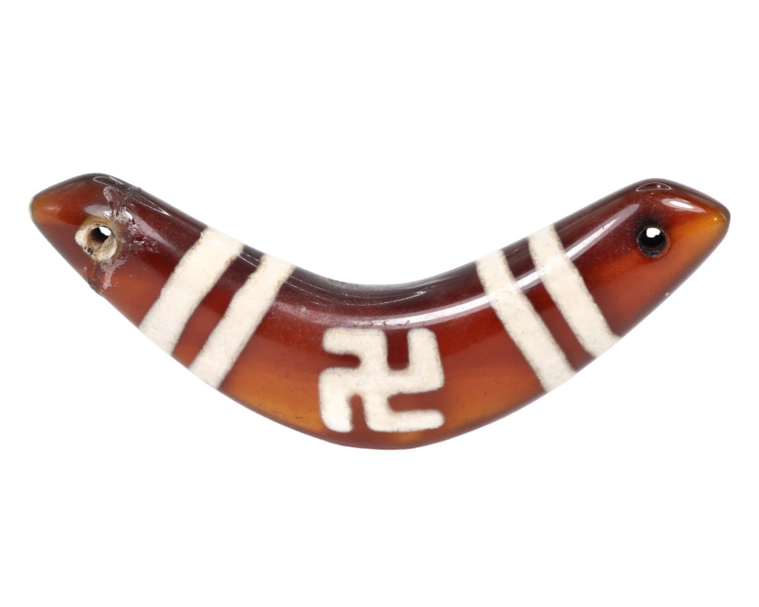 An Old Tibetan Etched Carnelian Bow Shaped Amulet: This bow shaped amulet, made from etched carnelian, exemplifies the intricate craftsmanship and spiritual significance of Tibetan culture. Such amulets were commonly used for protection and as talisma