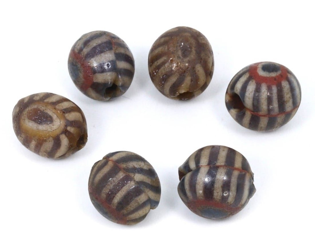 Group of Antique Parthian Mosaic Glass Beads, c. 247 BCE - 224 CE: This collection of shield-shaped beads, made from brown, tan, and olive mosaic glass. Dating back to the Parthian period (c. 247 BCE - 224 CE), it exemplifies the intricate craftsmanship and artistic