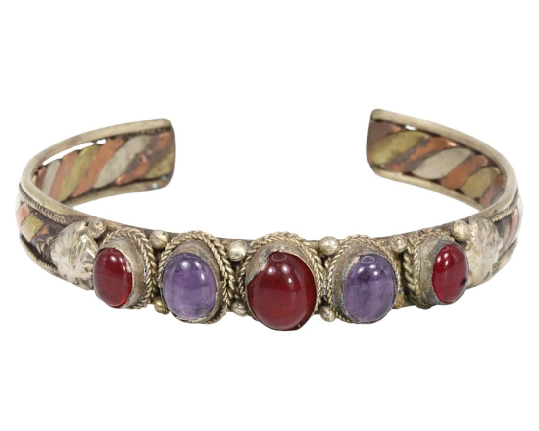 Traditional Tibetan Gilt Silver Carnelian and Amethyst Bracelet: This gilt silver bracelet, exemplifies the intricate craftsmanship and rich cultural heritage of Traditional Tibetan artistry. Featuring an elaborate design with inlaid stones including vibrant red ca
