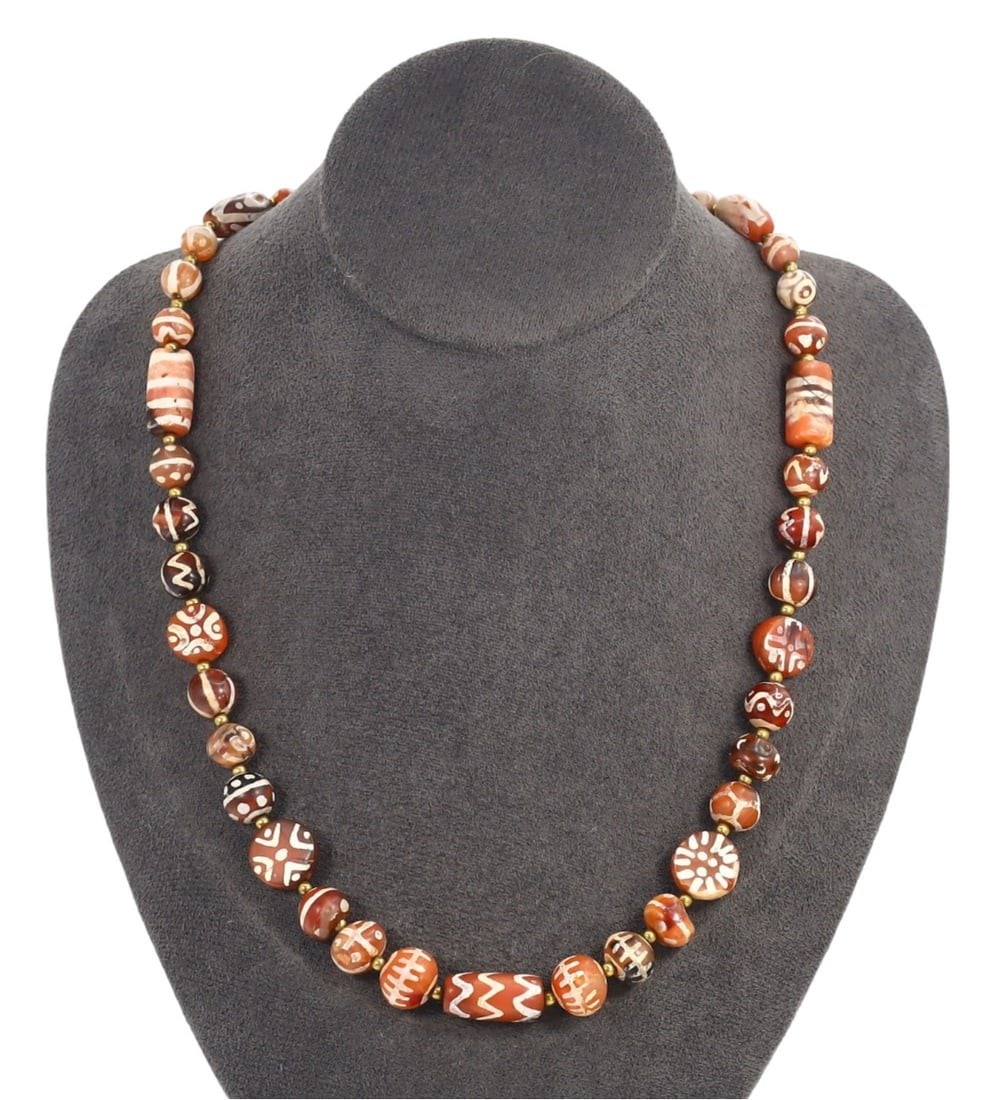 Antique Indo-Himalayan Tibetan Etched Carnelian Beaded Necklace: This etched carnelian beaded necklace exemplifies the meticulous craftsmanship and profound cultural significance of Tibetan art. Each bead, featuring a variety of round and cylindrical shapes, is ado