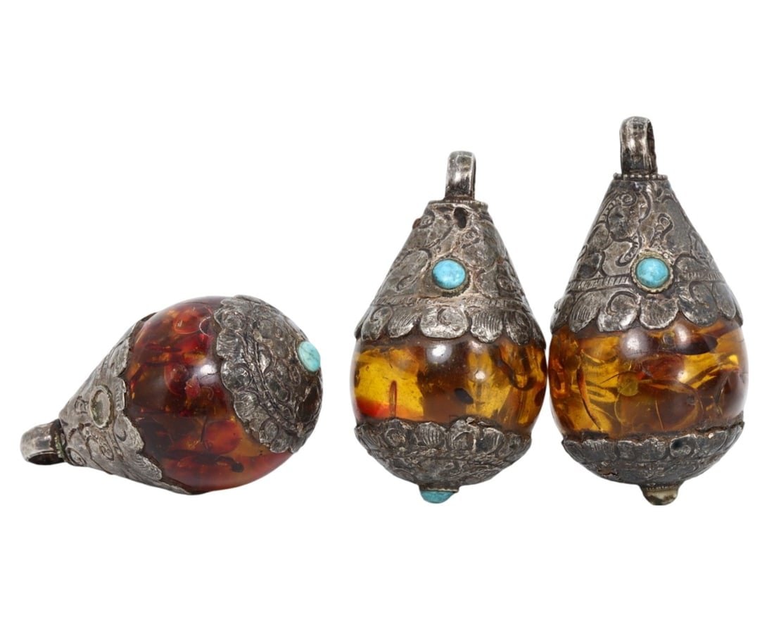 Vintage Tibetan Pressed Amber and Tribal Silver Lockets: This exquisite pressed amber and tribal silver locket exemplifies the masterful craftsmanship and rich cultural heritage of Tibetan artisans. Featuring three intricately crafted, drop-shaped amulets o