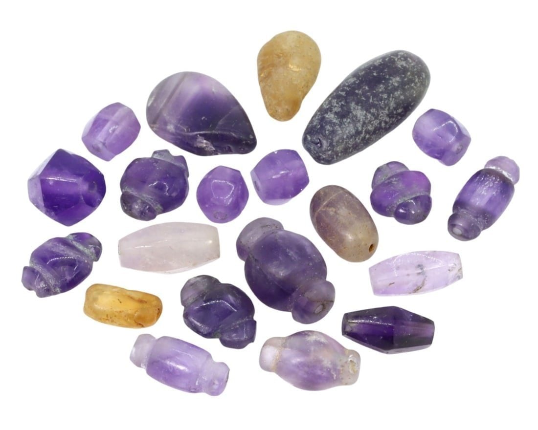 Collection of 21 Ancient Egyptian and Roman Period Amethyst and Quartz Beads: This exquisite collection of 21 ancient beads, made from amethyst and quartz, exemplifies the exceptional craftsmanship and cultural significance of both Egyptian and Roman societies. Such beads were 