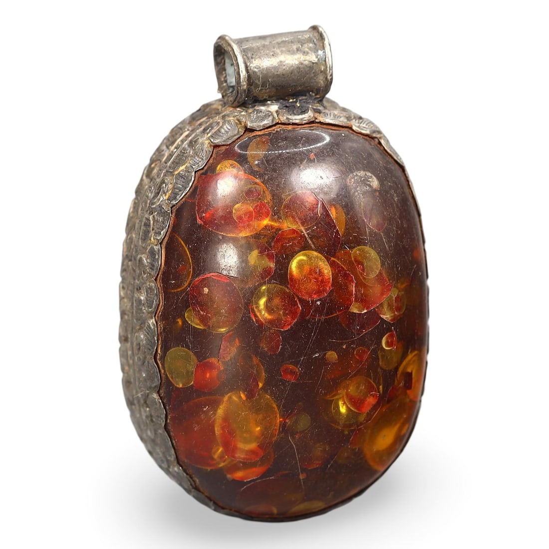 Post Medieval Sino Himalayan Tibetan Pressed Honey Amber Locket Pendant, 18th-20th Century: This exquisite locket pendant, dating from the 18th to the 20th century, originates from the Sino Himalayan Tibetan region. The pendant features a beautifully pressed honey amber, showcasing a rich an