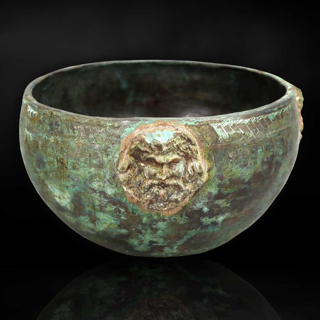 Ancient Roman Bronze Bowl with Bacchic Mask, 1st Century BCE - 1st Century CE: This captivating bronze bowl dates to the early Roman Empire, from the 1st century BCE to the 1st century CE, a period marked by Rome's consolidation of power and expansion of luxury arts. Roman artis