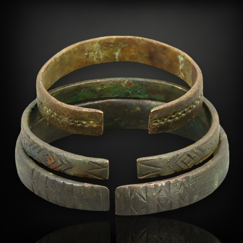 Ancient Celtic Geometric Bronze Cuff Bracelets Trio, c. 1st Century BCE - 1st Century CE: This rare trio of Celtic bronze cuff bracelets, dating from the 1st century BCE to the 1st century CE, exemplifies the geometric elegance and symbolic depth of ancient Celtic adornments. Each bracelet