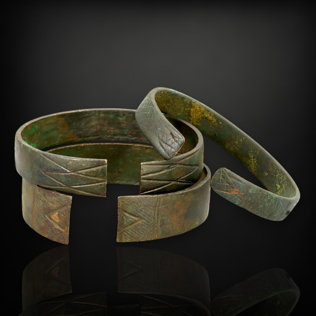 Ancient African Bronze Engraved Cuff Bracelets, c. 8th-12th Century CE: This exquisite collection of three ancient African bronze cuff bracelets, dating from the 8th to 12th century CE, captures the beauty and cultural heritage of early African societies. Each cuff is ado