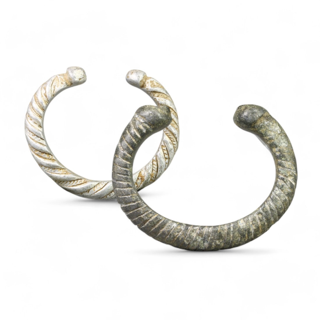 WEST AFRICAN: Pair of Silvered Twisted Snake Cuff Bracelets, 19th-20th Century CE (4.5-5.5cm, 58g): This distinguished pair of West African silvered snake cuff bracelets showcases intricate twisted designs along the rounded bands, culminating in stylized serpent-head terminals. The craftsmanship and