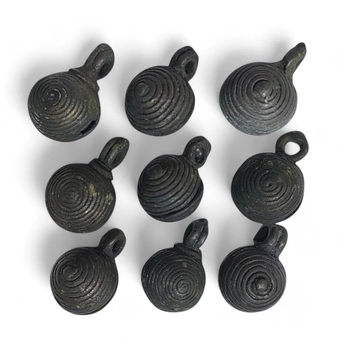 AFRICAN ANTIQUE BRONZE CROTAL BELLS: Lot of 9, 19th-20th Century CE (130g, 3cm each): This lot includes 9 antique African bronze crotal bells, each measuring 3cm and weighing a total of 130g. The bells are crafted with a distinctive spiral design and feature suspension loops for attach