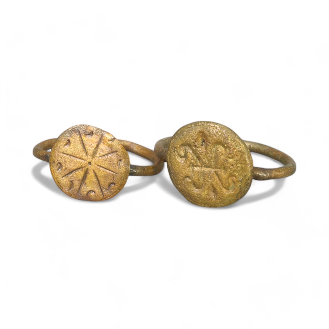 BYZANTINE ERA: Pair of Bronze "Solar Symbol and Christogram" Rings, 6th-9th Century CE (7-10 US, 7g): This elegant pair of bronze rings showcases distinct Byzantine motifs. One features a radiating solar symbol, likely representing divine light or eternal life, while the other bears a Christogram, an