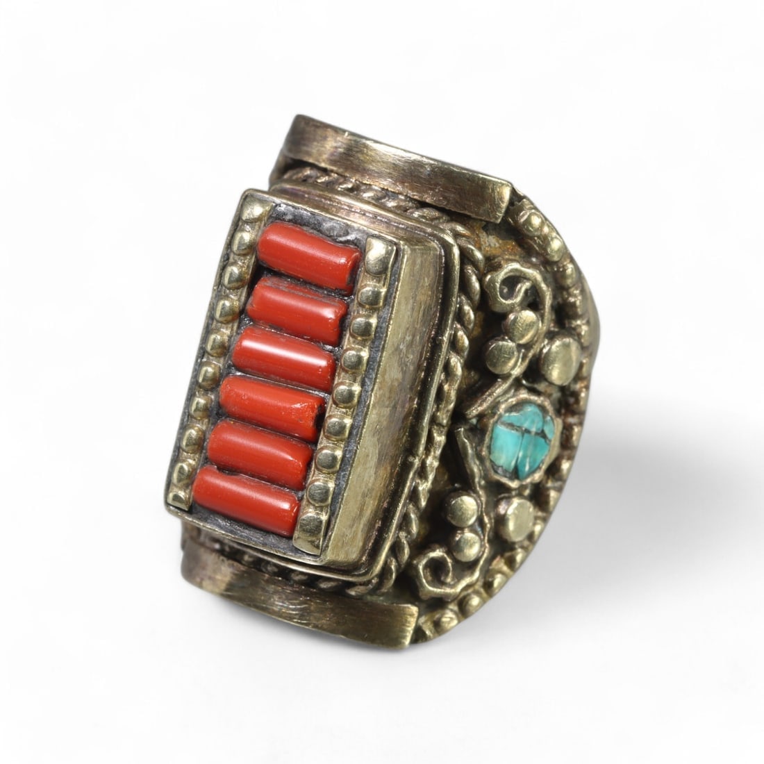 TIBETAN STYLE: Silver "Coral and Turquoise Harmony" Ring, 20th Century (30g, Size 10 US): This bold Tibetan-style silver ring showcases a striking design with seven vibrant coral inlays arranged in a rectangular bezel. The intricate band is adorned with detailed filigree and accented by a 