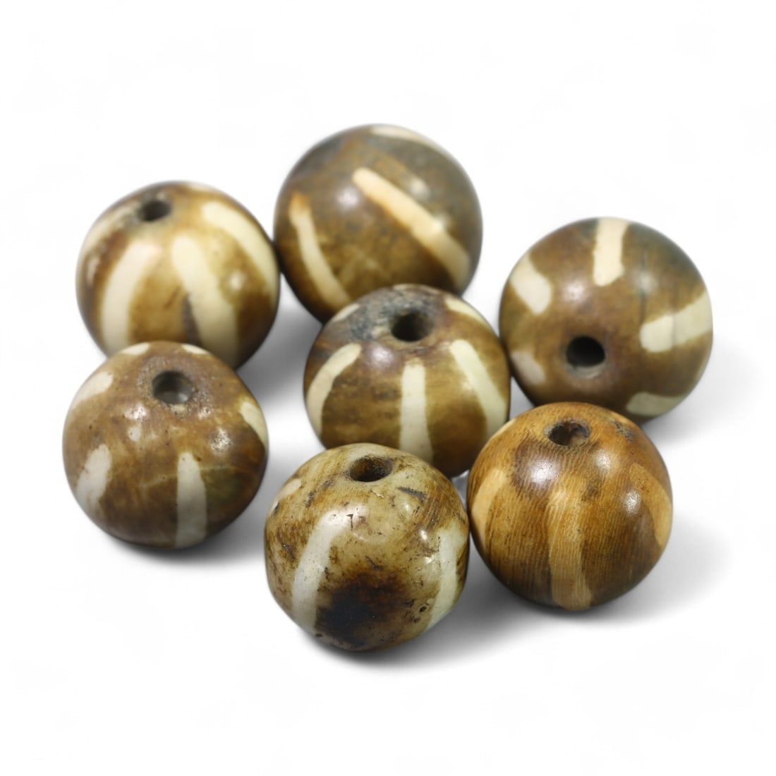 ANTIQUE TIBETAN: Pumtek Wood Beads with Radiating Motifs (22g, 15x14mm): This set of antique Tibetan Pumtek beads comprises seven beautifully crafted fossilized wood beads adorned with radiating cream-colored motifs on a rich brown base. The subtle patina and natural textu