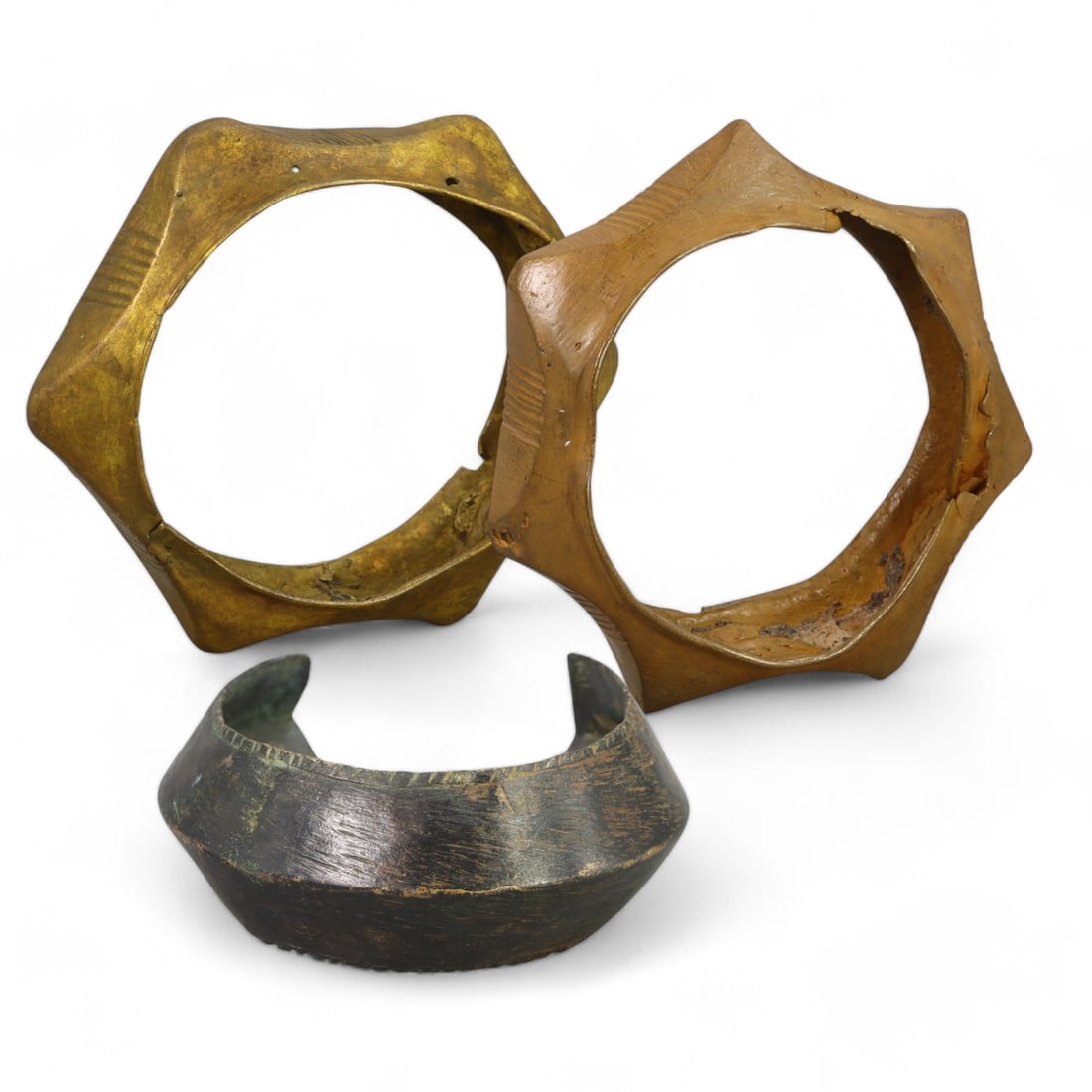 AFRICAN TRIBAL: Set of Three Bronze Bangles (200g total, 6-9cm each): This set of three African tribal bronze bangles showcases diverse craftsmanship with varying geometric designs and forms, including one with a striking star-like shape. The engraved patterns on two of