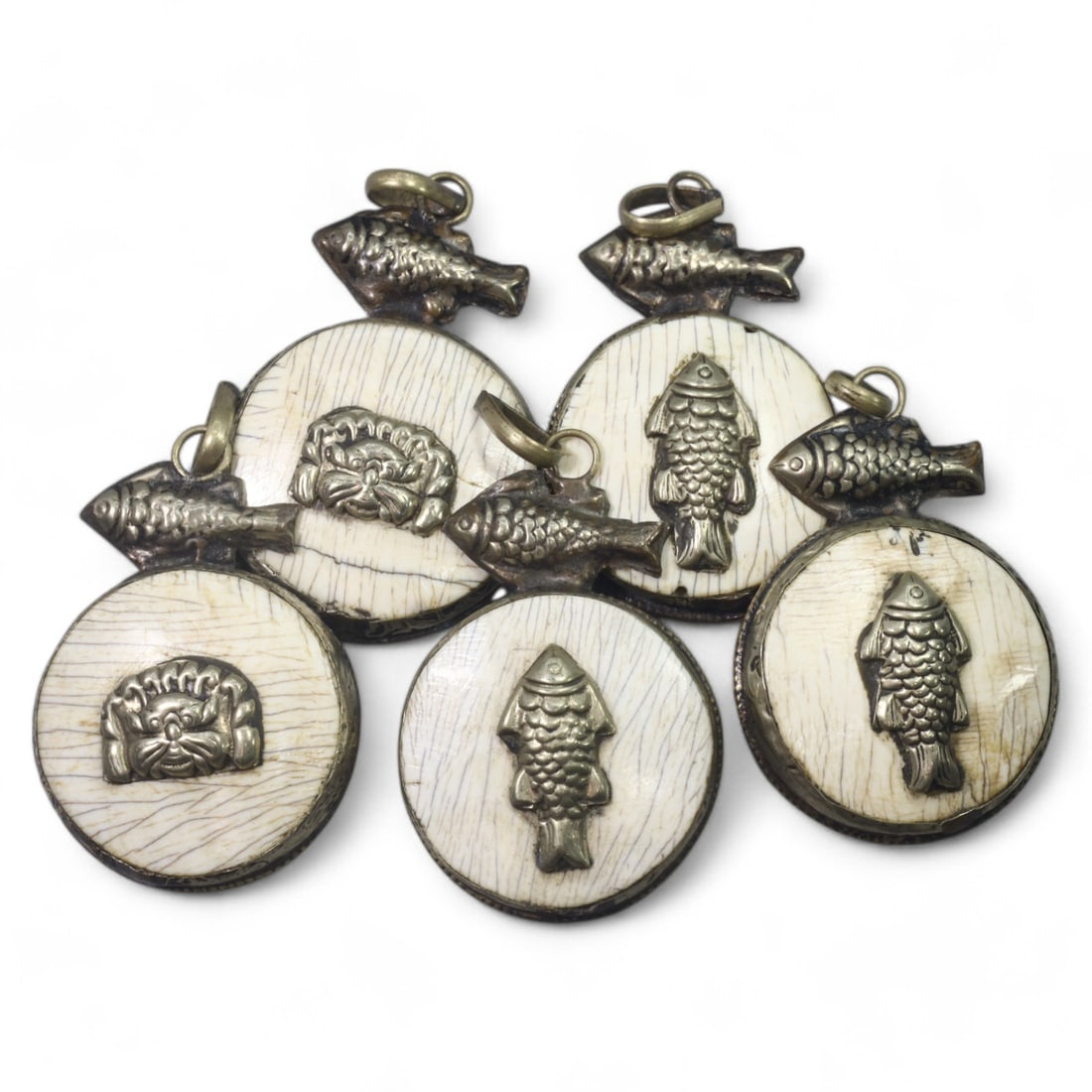 HIMALAYAN: Antique Carved Bone Amulets with Silver Fish Motifs (68g, 4.5cm): This remarkable set of carved bone amulets hails from the Himalayan region, featuring finely detailed silver adornments. Each amulet showcases a central mask motif, symbolizing protection or warding o