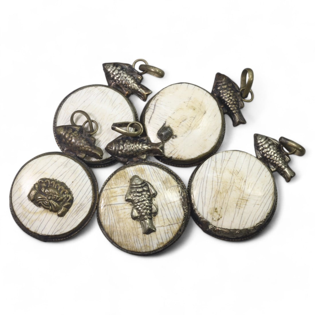 HIMALAYAN: Antique Carved Bone Amulets with Silver Fish Motifs (78g, 4.5cm): This remarkable set of carved bone amulets hails from the Himalayan region, featuring finely detailed silver adornments. Each amulet showcases a central mask motif, symbolizing protection or warding o