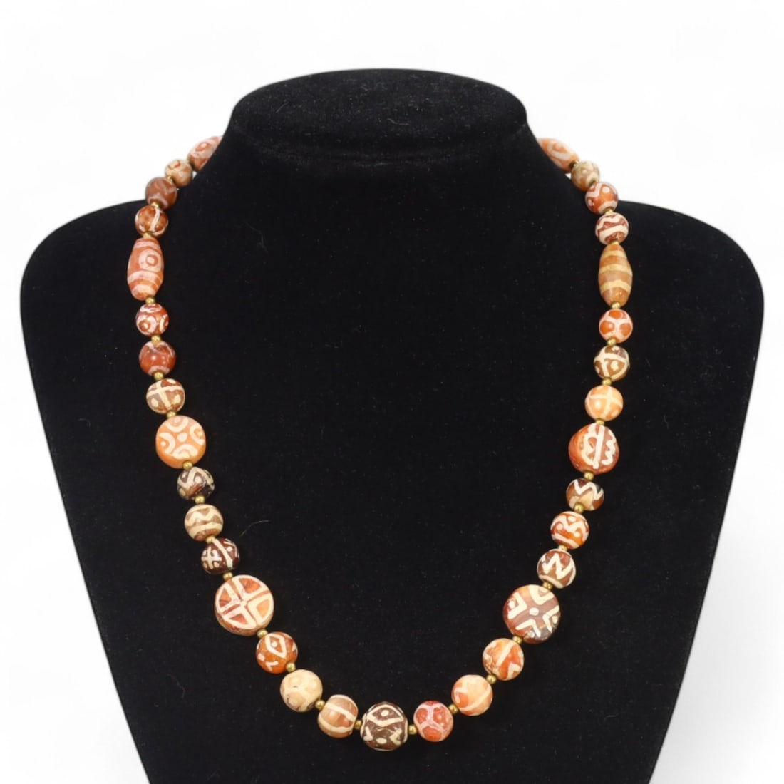 TIBETAN: Antique Etched Carnelian Dzi Beads Necklace, 19th-20th Century CE (57g, 51cm): This striking necklace features a strand of antique carnelian dzi beads, each intricately etched with traditional Tibetan motifs such as geometric patterns and eye designs, symbolizing protection and