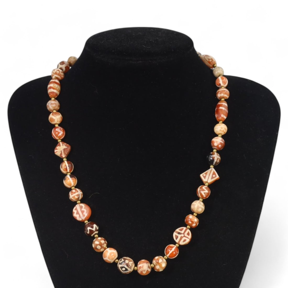 TIBETAN: Antique Etched Carnelian Dzi Beads Necklace, 19th-20th Century CE (50g, 49cm): This striking necklace features a strand of antique carnelian dzi beads, each intricately etched with traditional Tibetan motifs such as geometric patterns and eye designs, symbolizing protection and