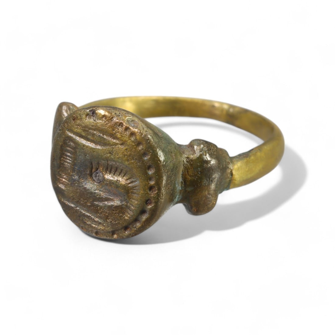 MEDIEVAL PERIOD: Heavily Embellished Bronze Signet Ring, 11th-14th Century CE (8g, Size 8.5 US): This remarkable medieval bronze signet ring features a large circular bezel adorned with a decorative motif, likely symbolic of personal or regional significance. Flanked by raised embellishments on e