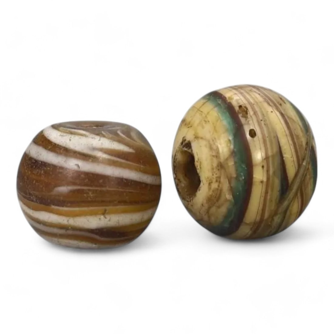 ANCIENT PERSIAN: Pair of Swirl Glass Beads, Circa 1st Millennium BCE (14g, 14-17mm): This pair of ancient Persian swirl glass beads features intricate patterns of alternating colors, meticulously crafted to display the artisanship of the time. Each bead showcases a unique design with 