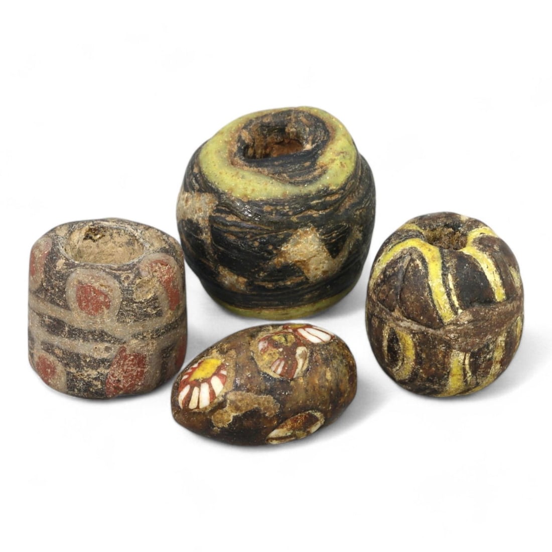 ROMAN ERA: Set of Four Polychrome Glass Beads, 1st-3rd Century CE (9g, 8-11mm, 4 Pieces): This charming set of four Roman polychrome glass beads exemplifies the variety and creativity of ancient bead-making. The collection includes cylindrical, spherical, and oval forms, each adorned with 