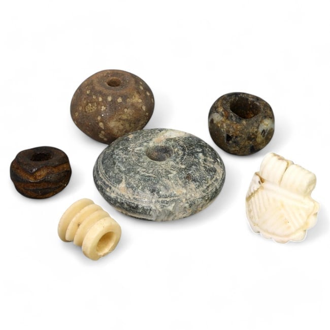 ANCIENT NEAR EASTERN BEADS AND SPINDLE WHORLS: Mixed Materials, Circa 2nd-1st Millennium BCE: This intriguing set includes a variety of ancient beads and objects, likely originating from the Near East. The collection features spindle whorls carved from stone, beads made of glass and stone, and