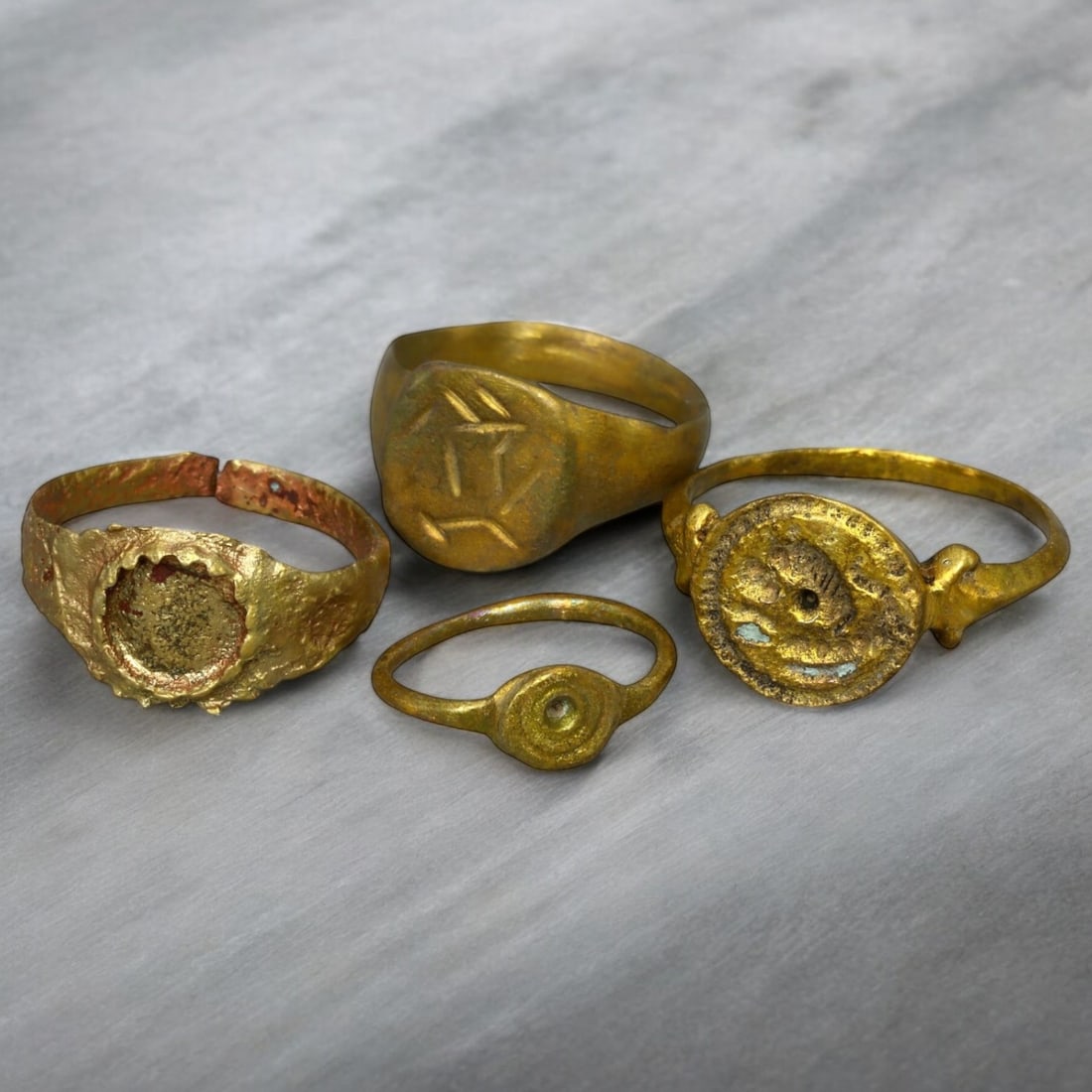 BYZANTINE ERA: Lot of Gilded Bronze Signet and Decorative Rings, Circa 6th-10th Century CE (10g,: This distinguished lot of Byzantine-era gilded bronze rings features four unique pieces, professionally cleaned to reveal their radiant golden finish. The collection includes intricately designed sign