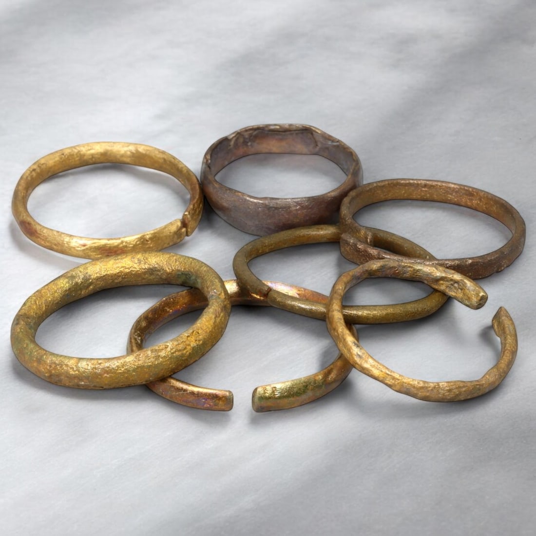VIKING ERA: Lot of Bronze Penannular and Solid Arm Rings, 9th-11th Century CE (19g, 7-10 US, 7 pcs): This captivating lot of Viking-era bronze arm rings consists of seven unique pieces, professionally cleaned to reveal their original golden bronze tones alongside rich natural patinas. The collection 