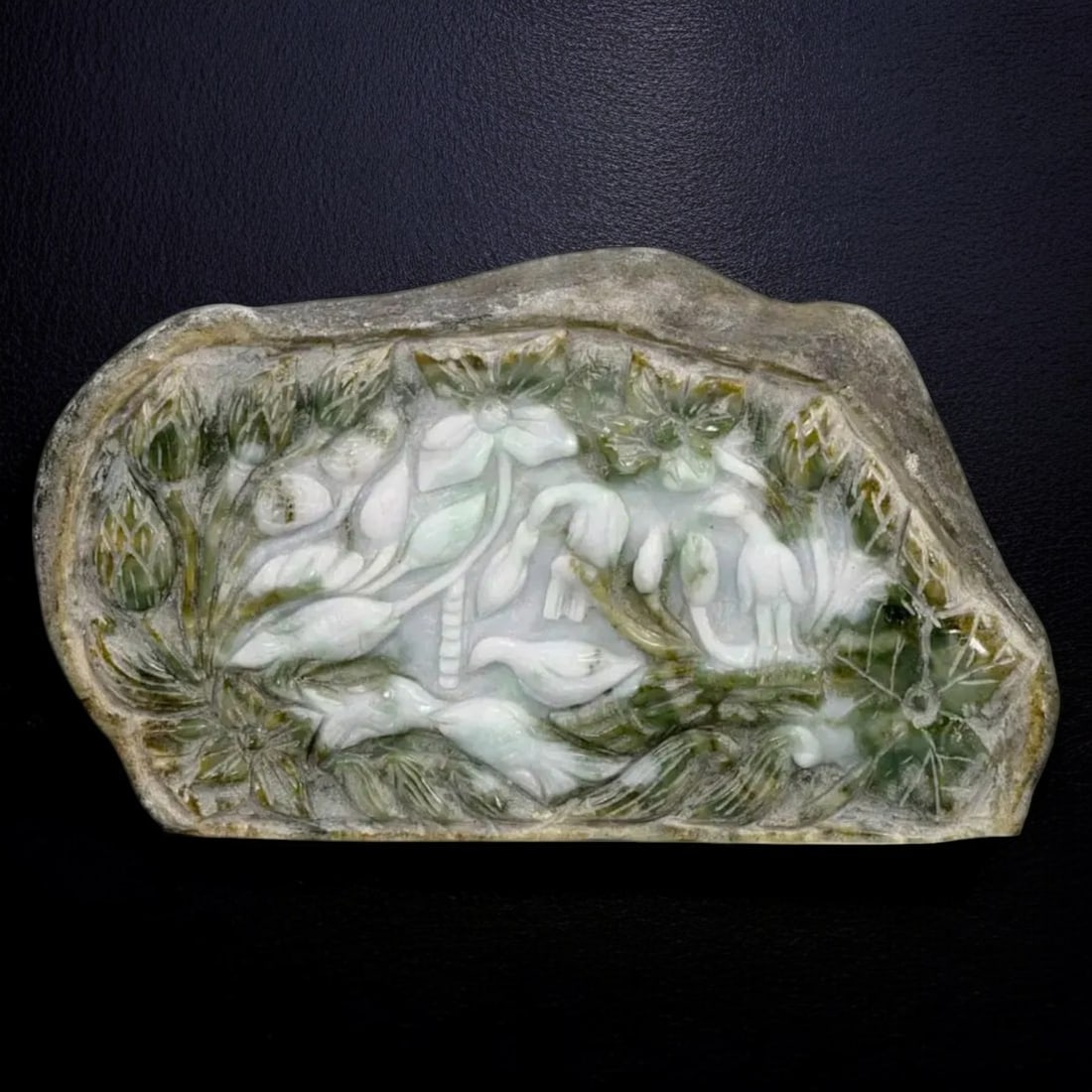 BURMESE ARTIFACT: Carved Jadeite Plaque with Botanical and Avian Motifs, (2459g, 23x12cm): This exceptional Burmese jadeite plaque, weighing 2459 grams and measuring 23 cm by 12 cm, showcases masterful carving with intricate botanical and avian motifs. The high-relief design depicts a harmo