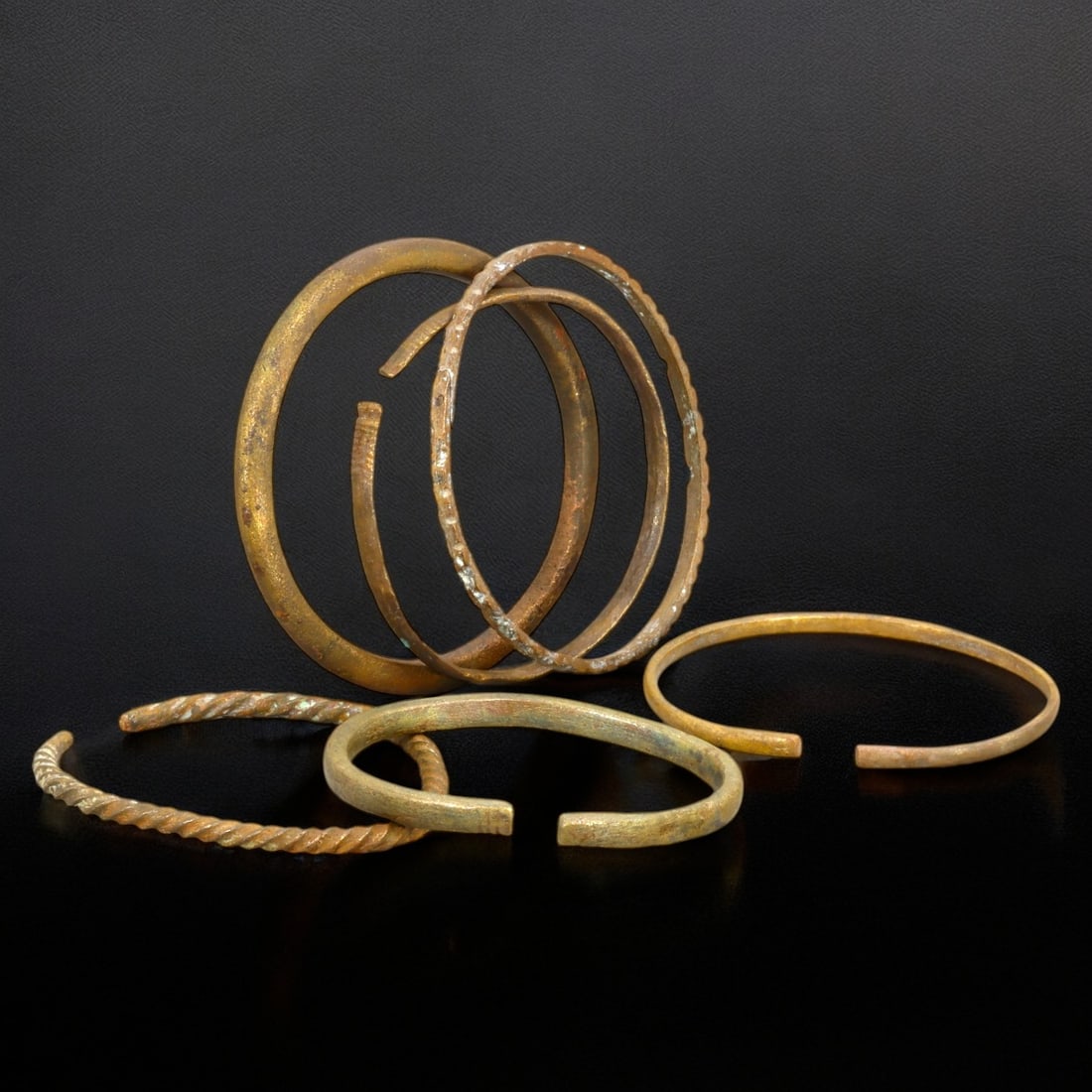 ANTIQUE BRONZE BRACELETS: Lot of Bronze Adornments (106g, 6-7cm): This lot features a collection of antique bronze bracelets, showcasing diverse styles and craftsmanship reflective of different cultural influences. The bracelets vary slightly in size and design, wit