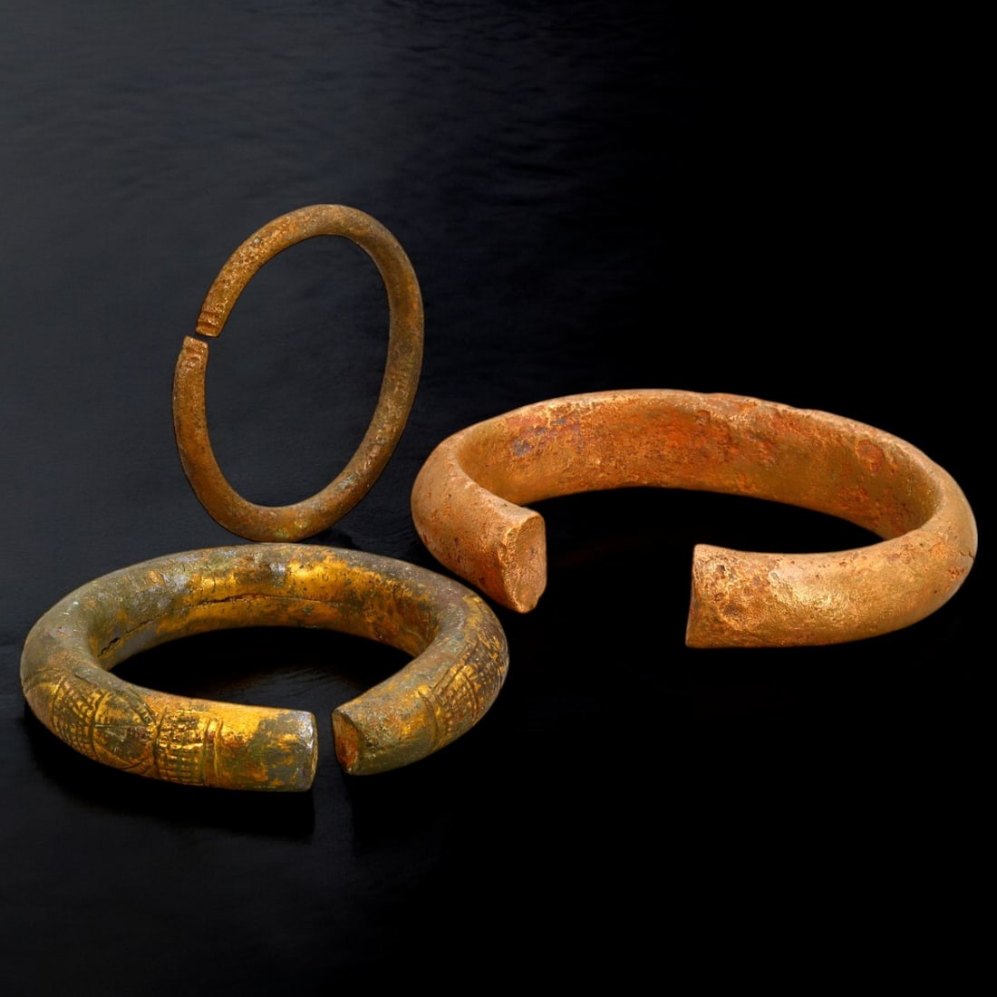 ANTIQUE BRONZE BRACELETS: Lot of Bronze Adornments (710g, 6-10cm): This lot features a collection of antique bronze bracelets, showcasing diverse styles and craftsmanship reflective of different cultural influences. The bracelets vary slightly in size and design, wit