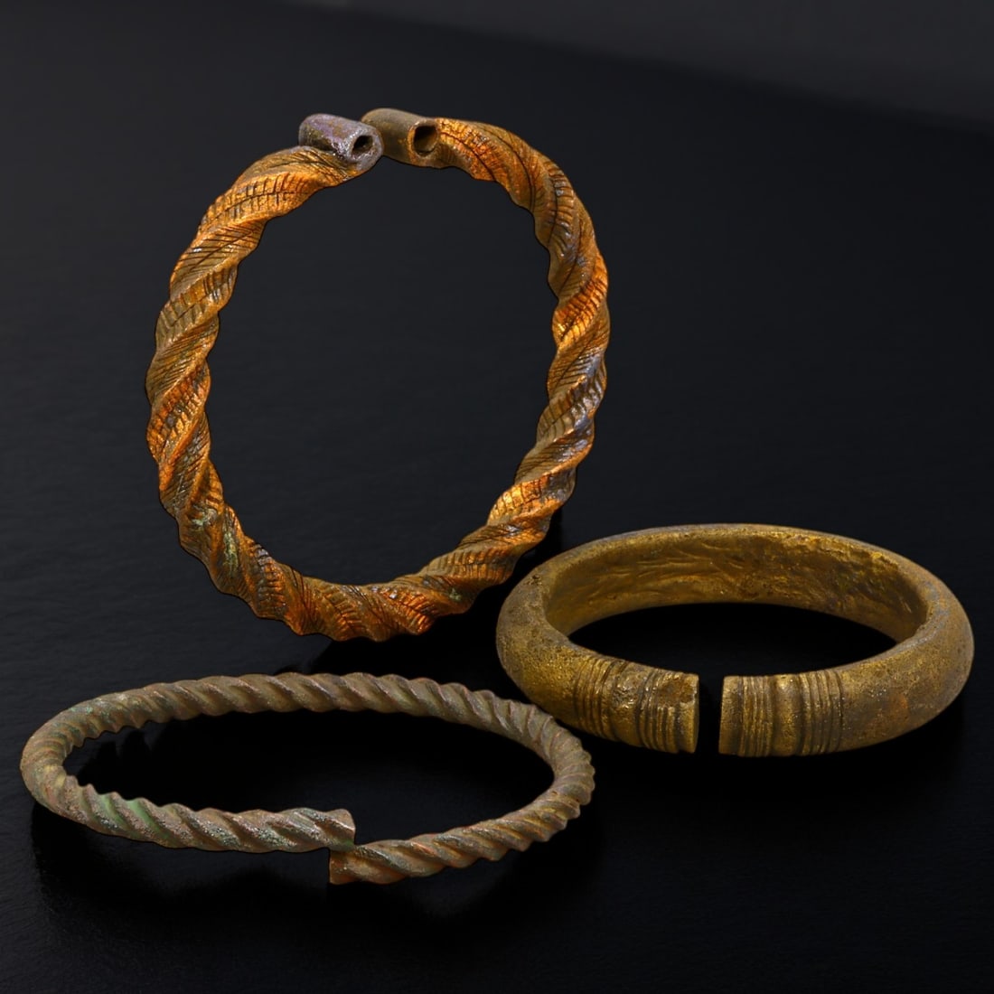 ANTIQUE BRONZE BRACELETS: Lot of Bronze Adornments (314g, 7-9cm): This lot features a collection of antique bronze bracelets, showcasing diverse styles and craftsmanship reflective of different cultural influences. The bracelets vary slightly in size and design, wit