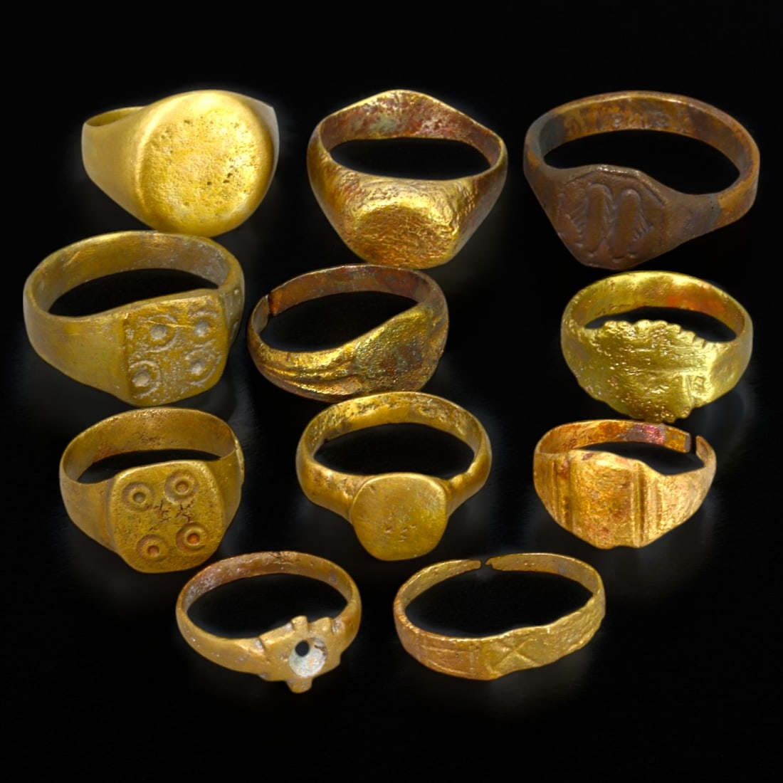 ANCIENT BRONZE RINGS: Gilded Bronze with Engraved Motifs (49g, US Sizes 5-11): This collection of ancient bronze rings showcases a variety of designs, featuring smooth, rounded bezels, engraved geometric motifs, and traces of gilding that hint at their former luster. These rings