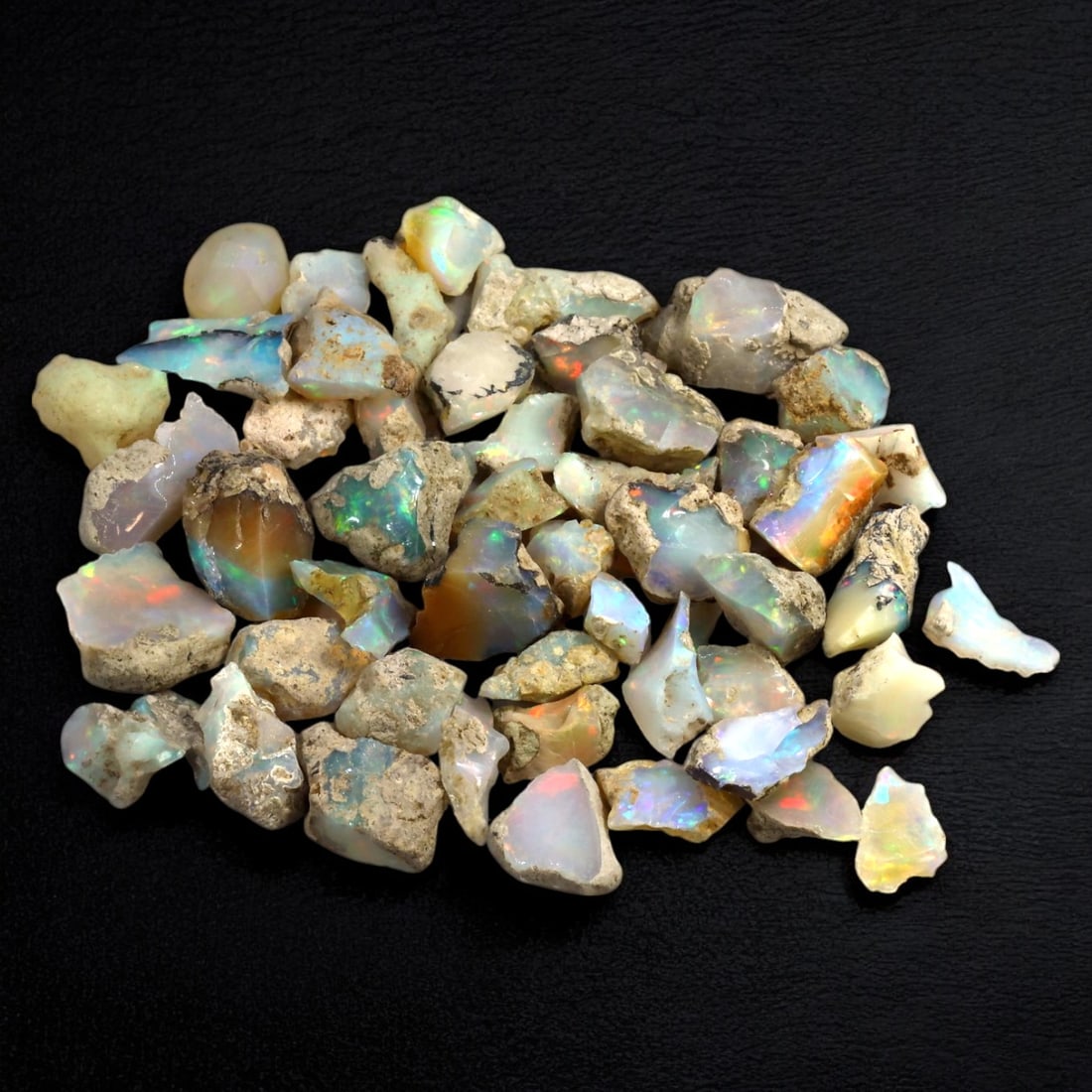 ETHIOPIAN WELO OPAL: Lot of Hydrophane Opal Rough Stone, Ethiopia (49g, 12-20mm): This captivating lot of Ethiopian Welo opal rough showcases the mesmerizing play-of-color characteristic of hydrophane opals. Displaying vibrant flashes of red, green, blue, and orange within their tr