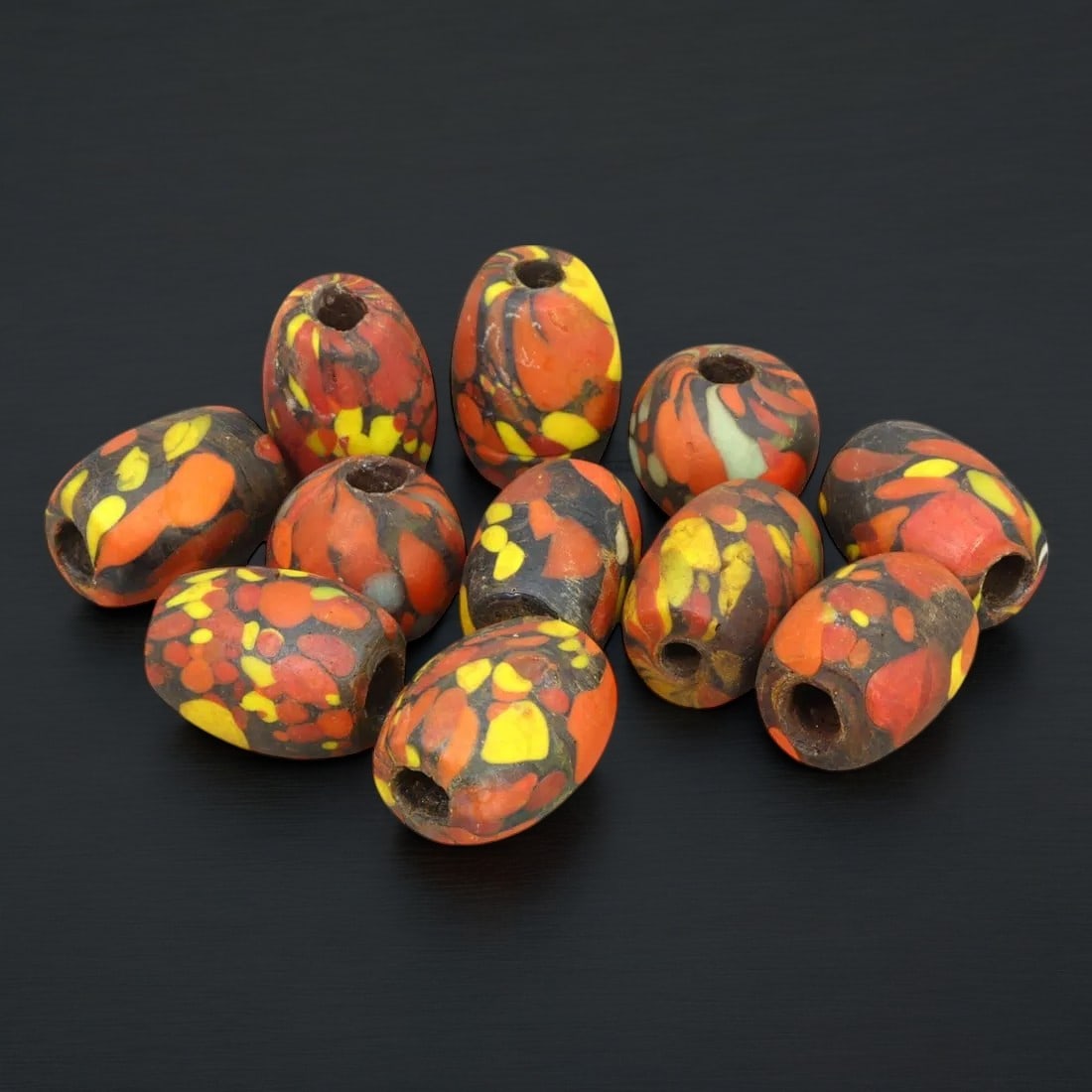 VENETIAN TRADE BEADS: Antique Glass Beads Lot, Sub-Saharan Africa (107g, 2-2.5cm, 11 pieces): This eye-catching lot features 11 antique Venetian trade beads with vibrant mosaic-like designs in red, yellow, and black hues. Known for their durability and intricate patterns, these beads were craf
