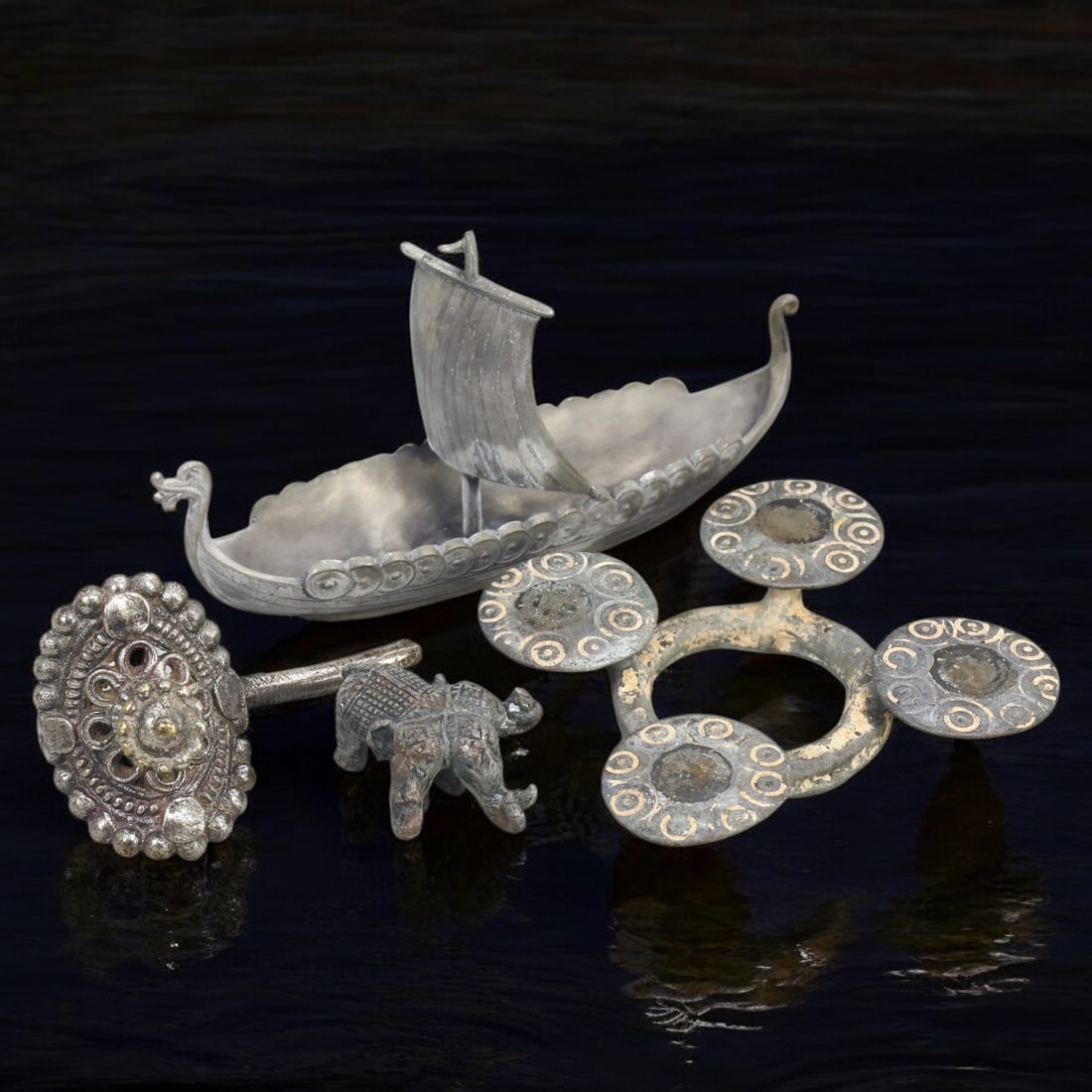 SILVERED ALLOY AND PEWTER ARTIFACTS LOT: Assorted Decorative Objects (316g, 7-12 cm): This captivating lot includes intricately crafted items made from silvered alloy and pewter, featuring a Viking-inspired longship with detailed carvings, an ornate circular brooch with beadwork, a min