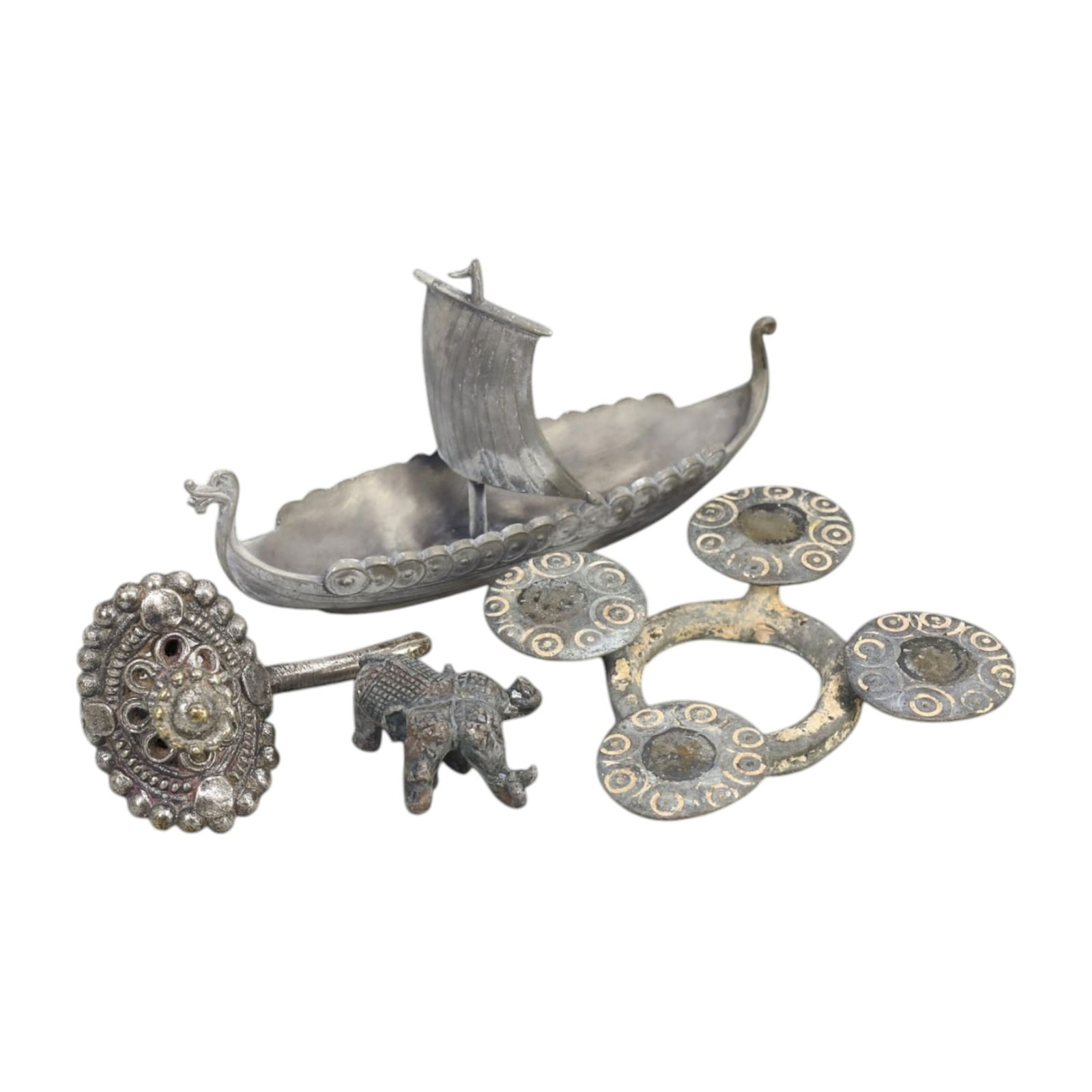 SILVERED ALLOY AND PEWTER ARTIFACTS LOT: Assorted Decorative Objects (316g, 7-12 cm): This captivating lot includes intricately crafted items made from silvered alloy and pewter, featuring a Viking-inspired longship with detailed carvings, an ornate circular brooch with beadwork, a min