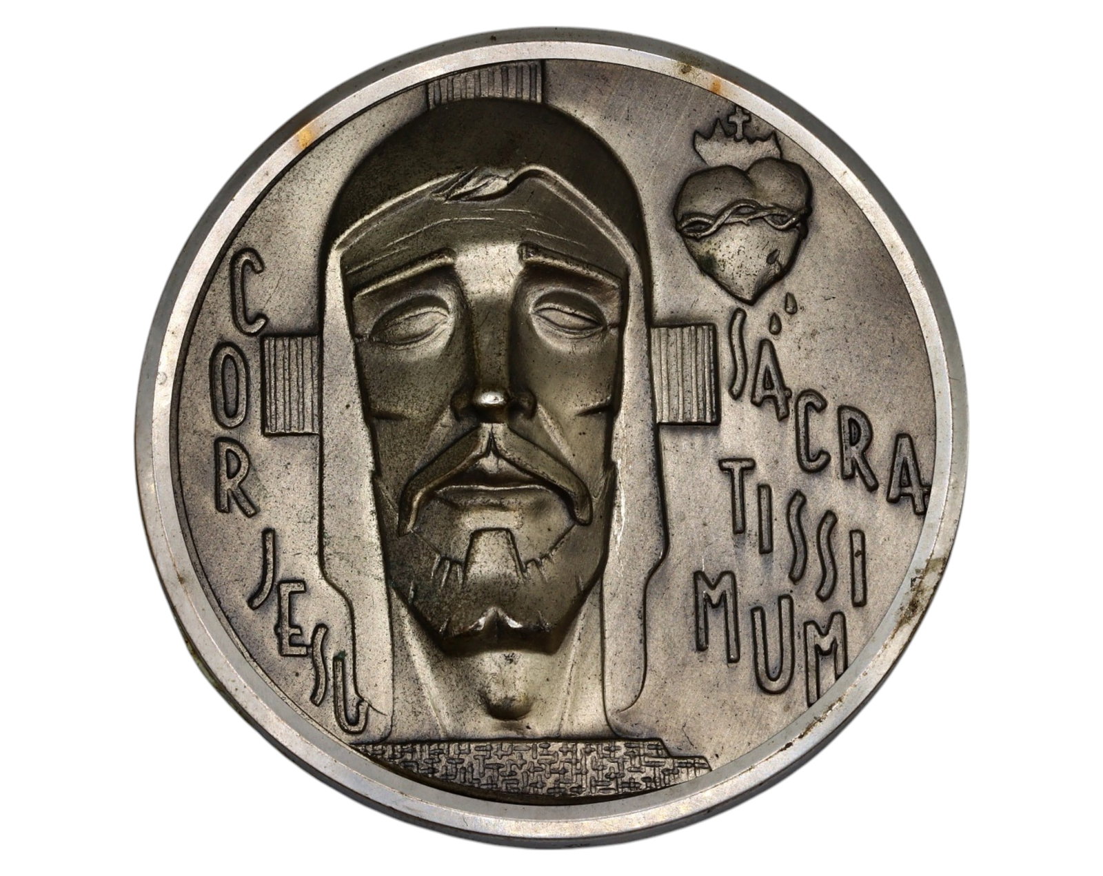 SACRED HEART OF JESUS MEDAL PLAQUE - Art Deco Style, Silvered Bronze, 20th Century: A striking silvered bronze devotional plaque depicting Christ in an Art Deco-inspired relief, measuring 6 cm in diameter and weighing 22g. The bold geometric lines and stylized lettering of COR JESU S