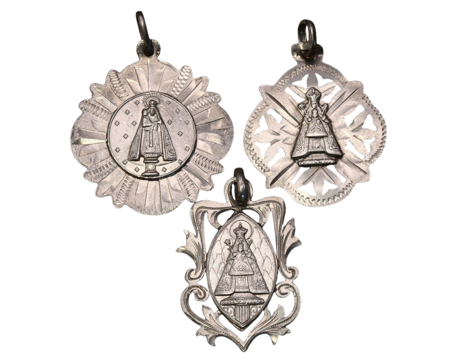 SPAIN: Our Lady of Montserrat & Virgin of Remedies - Silver Medals (19th-20th C): A finely crafted set of three silver devotional medals, each featuring distinct artistic openwork designs and intricate depictions of the revered Marian figures. The medals, measuring approximately 2.