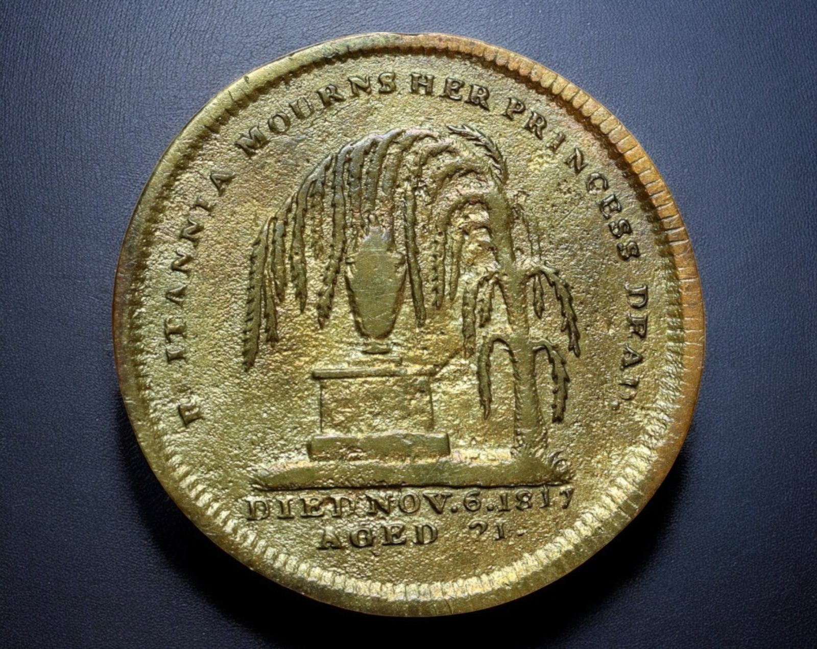 GREAT BRITAIN: Princess Charlotte Memorial Coin - Gilt Bronze, 25mm, 5.1g, 1817: A poignant memorial token struck to commemorate the untimely death of Princess Charlotte of Wales in 1817. The obverse features a left-facing bust of the princess, inscribed "THE PRINCESS CHARLOTTE", 