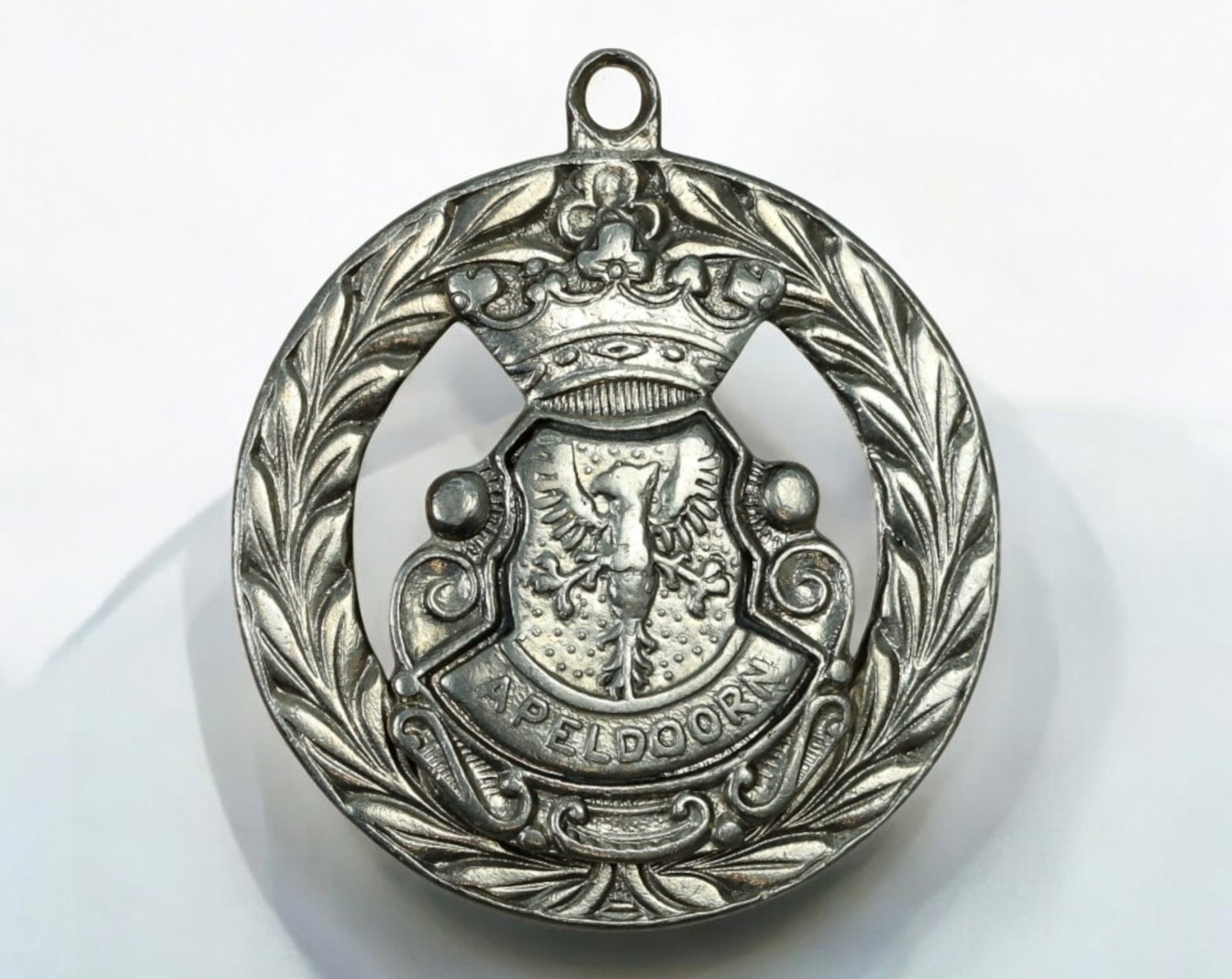 NETHERLANDS: Apeldoorn Coat of Arms Medallion - Silvered Metal, 35mm, 11.2g: A decorative medallion featuring the coat of arms of Apeldoorn, Netherlands, crafted in silvered metal, measuring 35mm in diameter and weighing 11.2g. The obverse presents a finely detailed heraldic s