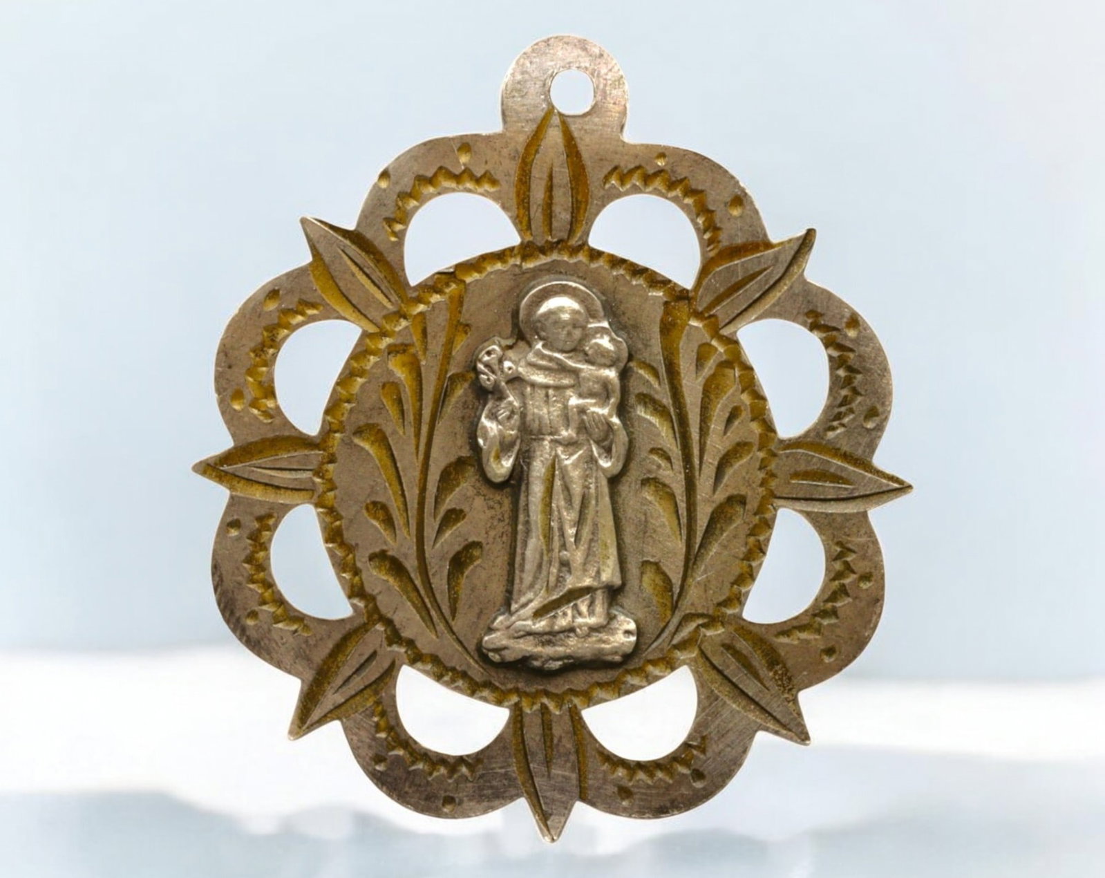 FRANCE: Saint Anthony of Padua Medal - Patron of Lost Things, Early 20th Century: A 3 cm, 2-gram finely crafted devotional medal depicting Saint Anthony of Padua holding the Christ Child, a representation of his renowned visions and deep connection to Christ. The intricate filigree