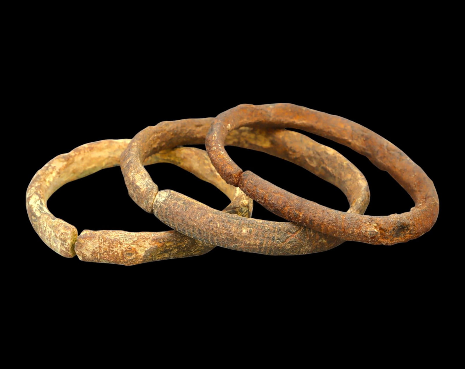 ANCIENT EUROPE: Set of Three Bronze and Iron Bracelets - Celtic, c. 5th-2nd Century BCE: A remarkable set of three ancient Celtic bracelets, measuring between 6-6.7 cm in diameter and weighing a combined 124g. Two are crafted from bronze, exhibiting a naturally aged patina, while the thir