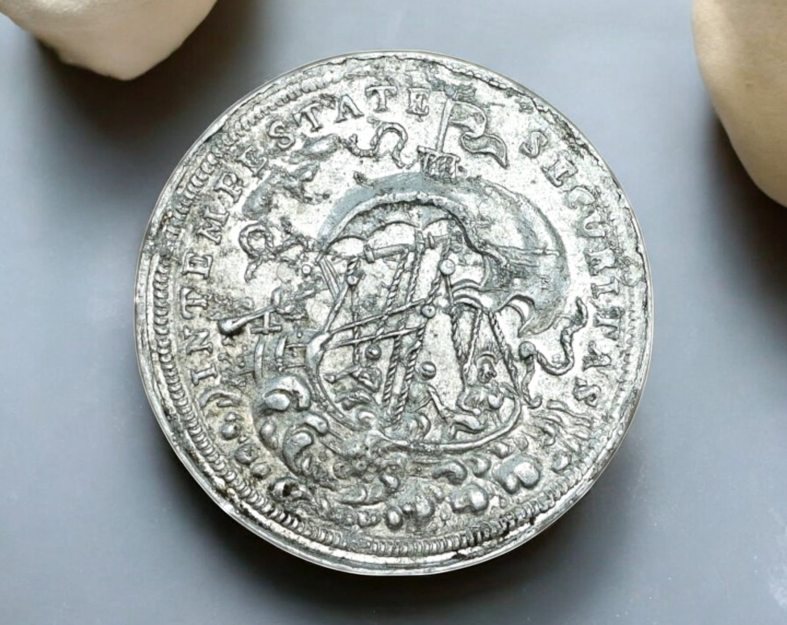GERMANY: St. George & Shipwreck Jeton - Aluminum Token, 19th-20th Century: An aluminum jeton or commemorative token, measuring 24mm in diameter, featuring religious and maritime motifs. The obverse depicts a shipwreck scene with maritime elements, inscribed IN TEMPESTATE SEC