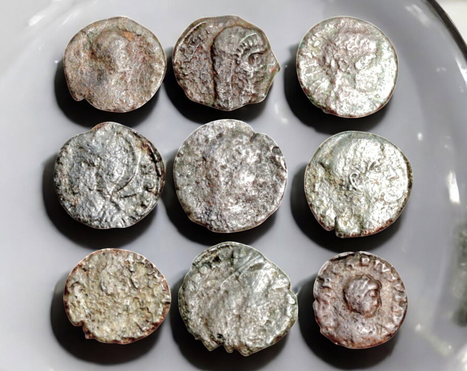 ROMAN EMPIRE: AE Coins - Bronze Coins, 12-14mm, 10.4g (Lot of 9): A collection of ancient Roman bronze coins, each featuring a distinct imperial portrait on the obverse and various symbolic or military-themed reverses. These coins, essential to Roman commerce and go