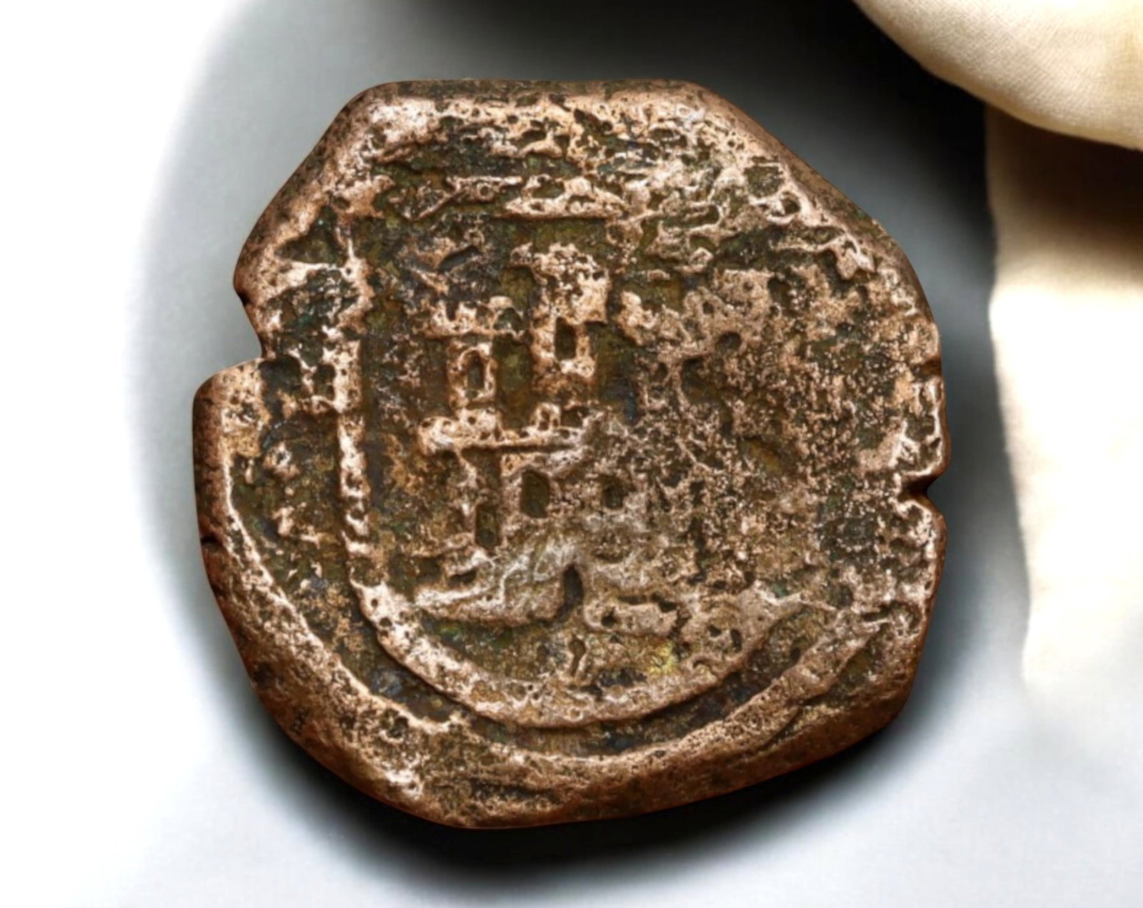 SPAIN: Philip II Copper Maravedis - Coruna Mint, 1556-1598: A 20mm, 4.8g copper maravedis struck during the reign of Philip II of Spain (1556-1598) at the Coruna Mint. The obverse displays a crowned monogram of Philip II, surrounded by remnants of the original