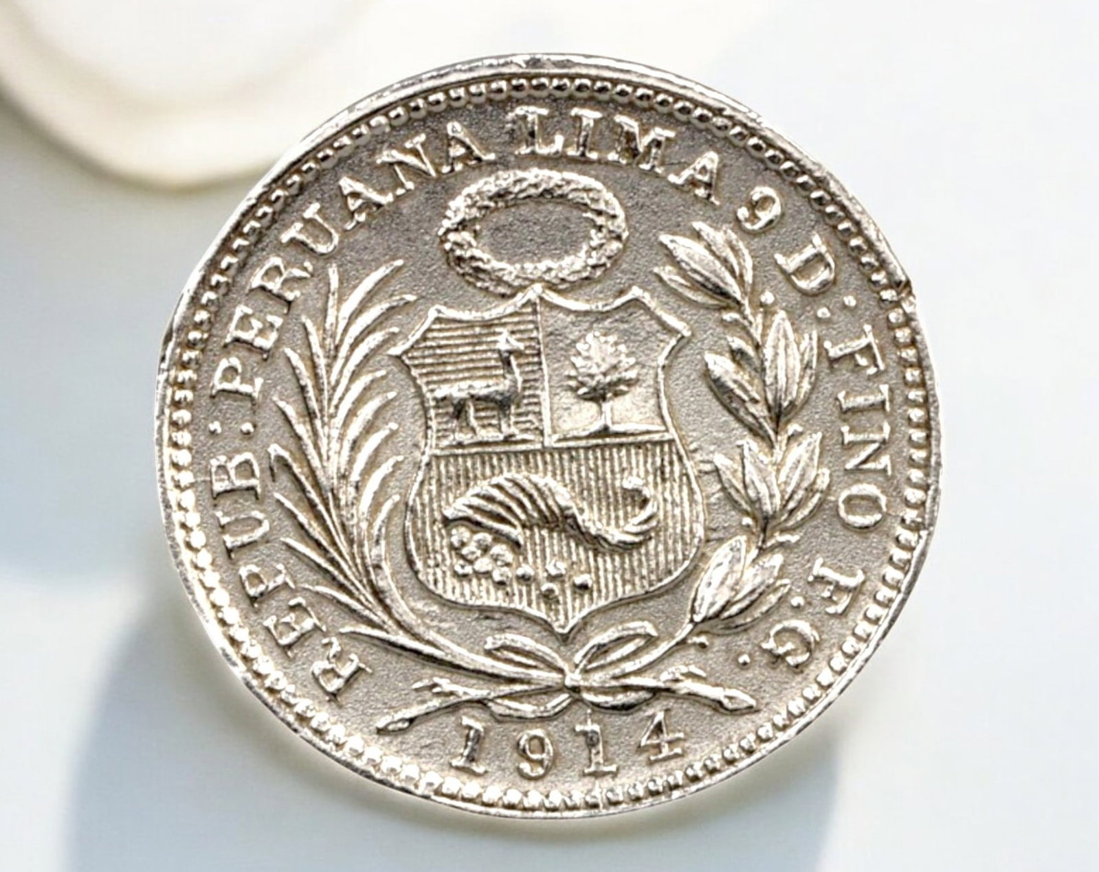 PERU: Silver 1/2 Dinero Coin - 1914, Lima Mint: A well-preserved silver 1/2 Dinero from Peru, struck in 1914 at the Lima Mint. Measuring 15mm in diameter and weighing 1.2g, this small yet elegant coin features the Peruvian coat of arms on the obver
