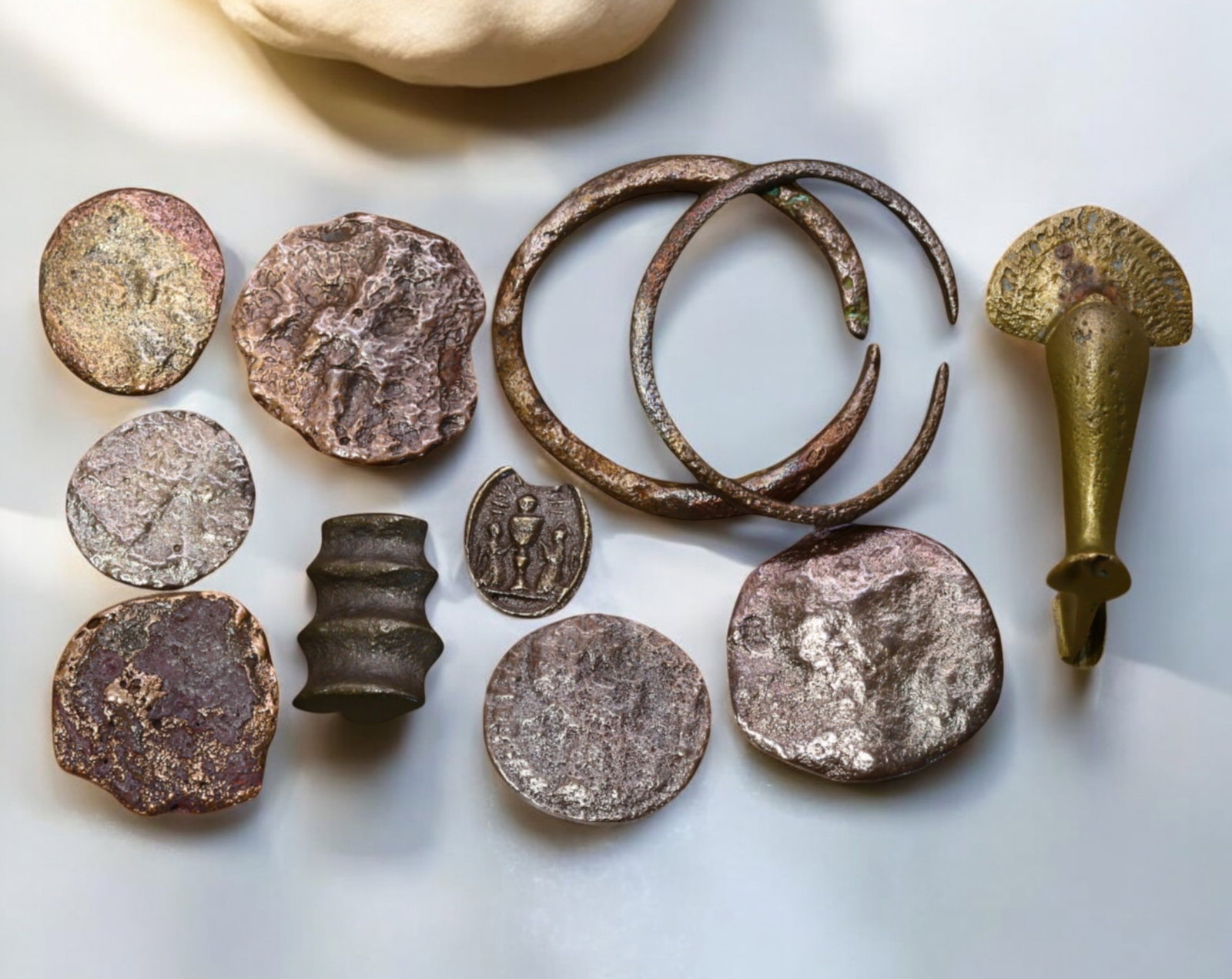 ANCIENT EUROPE: Bronze & Iron Currency and Artifacts - 1st Millennium BC to AD: An intriguing collection of 11 ancient bronze and iron artifacts, ranging in size from 1.1 cm to 3.2 cm and weighing 37 grams in total. This lot features a mix of proto-money, coinage, and ornamental 