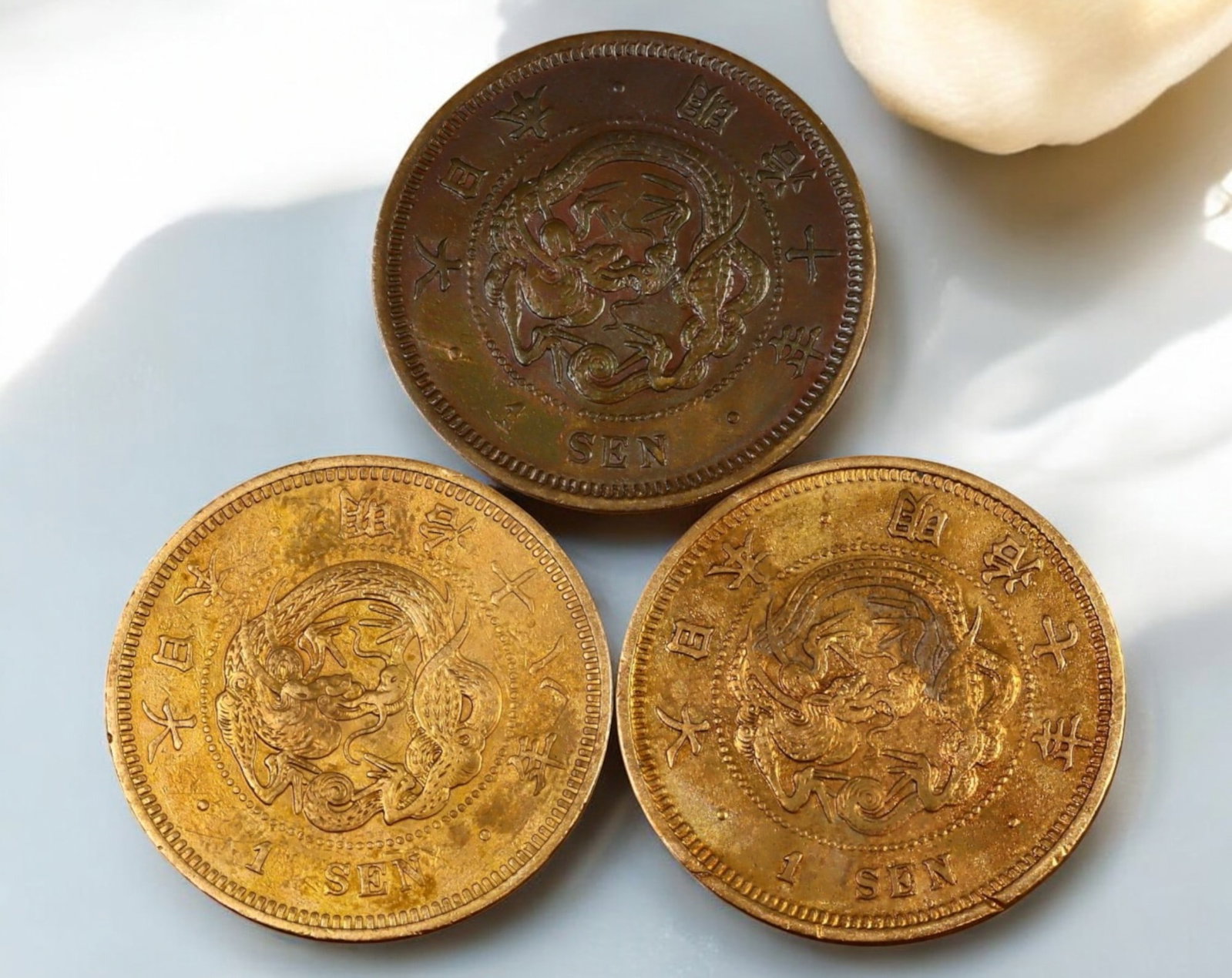 JAPAN: Meiji Era 1 Sen Coin - Copper, Year 7, 10, 18 (1874, 1877, 1885): A trio of Meiji-period 1 Sen coins, struck in copper, each weighing 7.13g with a diameter of 27.9mm. These coins, issued under Emperor Mutsuhito (Meiji), feature a bold depiction of a coiled dragon on