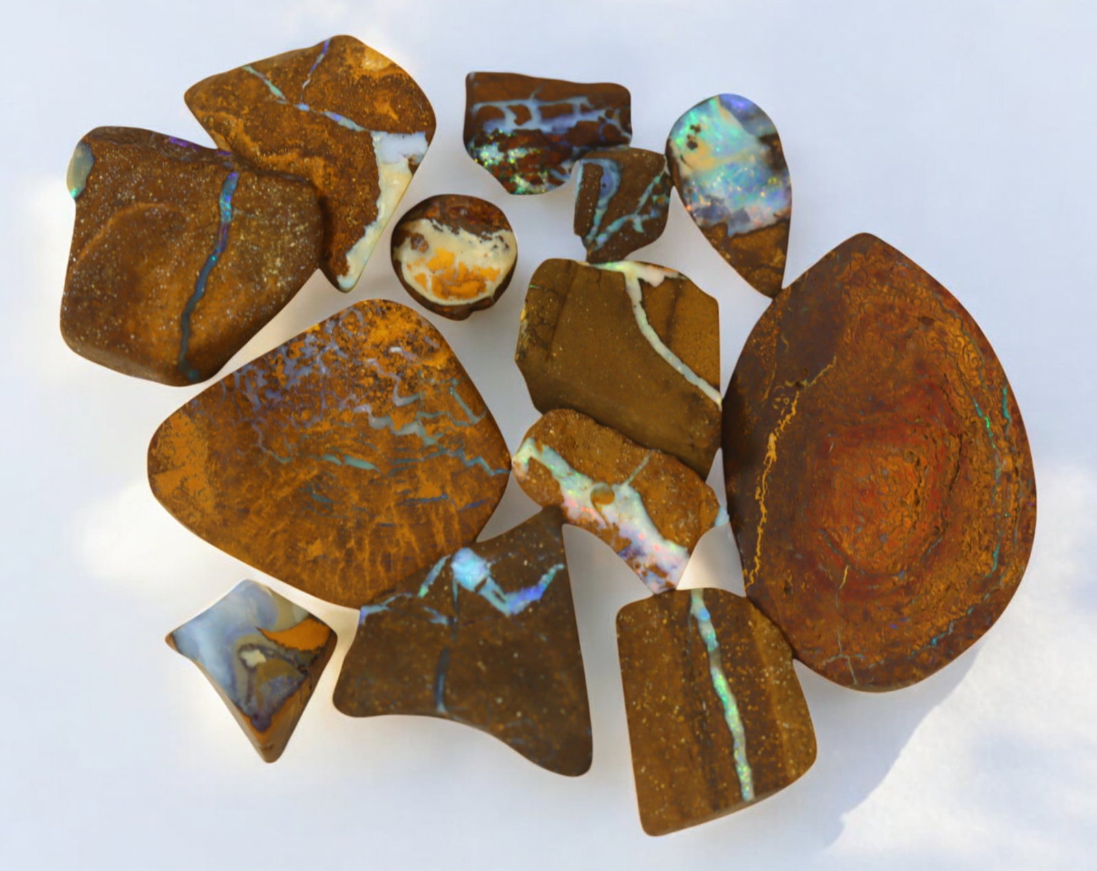 AUSTRALIAN MATRIX BOULDER OPAL - Rough Lot, 41g, 1-3cm (Images Taken Wet): A striking lot of natural Australian matrix boulder opal rough. These raw specimens display mesmerizing flashes of blue, green, and gold veins running through ironstone, characteristic of high-quality