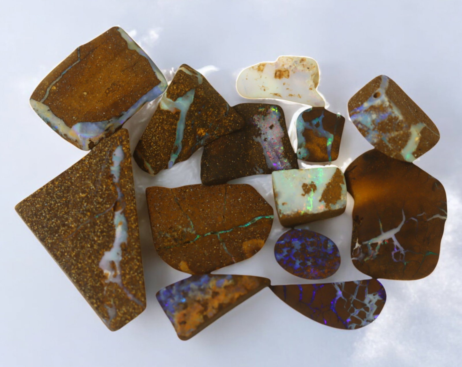 AUSTRALIAN MATRIX BOULDER OPAL - Rough Lot, 27g, 1-3cm (Images Taken Wet): A striking lot of natural Australian matrix boulder opal rough. These raw specimens display mesmerizing flashes of blue, green, and gold veins running through ironstone, characteristic of high-quality