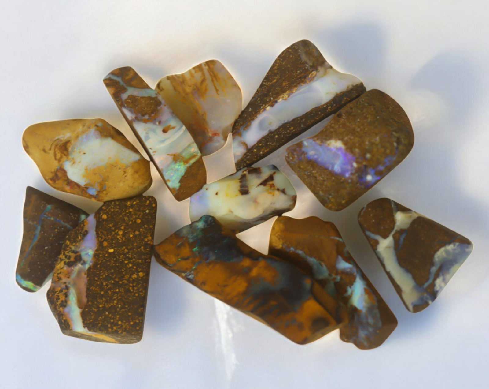 AUSTRALIAN MATRIX BOULDER OPAL - Rough Lot, 26g, 1-3cm (Images Taken Wet): A striking lot of natural Australian matrix boulder opal rough. These raw specimens display mesmerizing flashes of blue, green, and gold veins running through ironstone, characteristic of high-quality